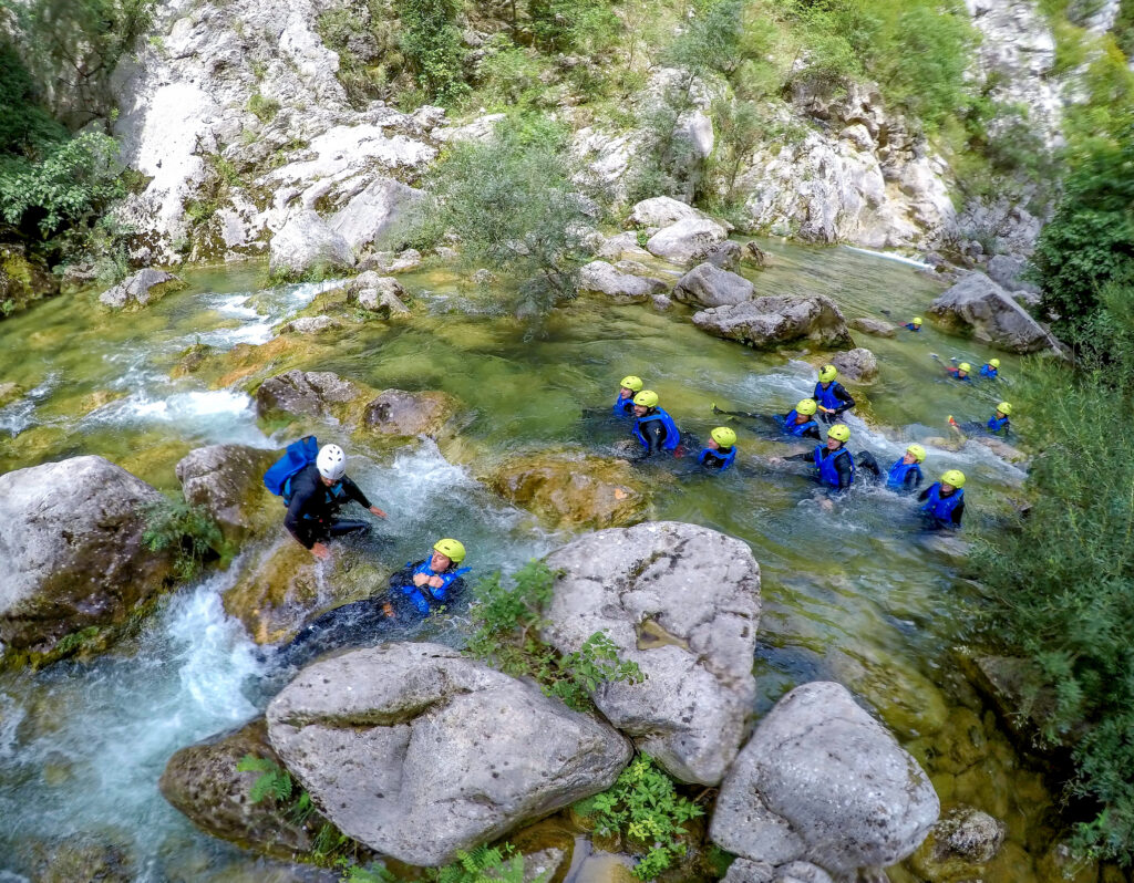 canyoning in a river group of people with blue life vests and yellow helmets