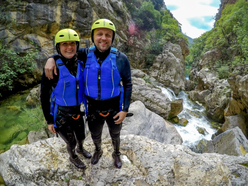 man and woman couple canyoning in croatia blue life vests and yellow helmets