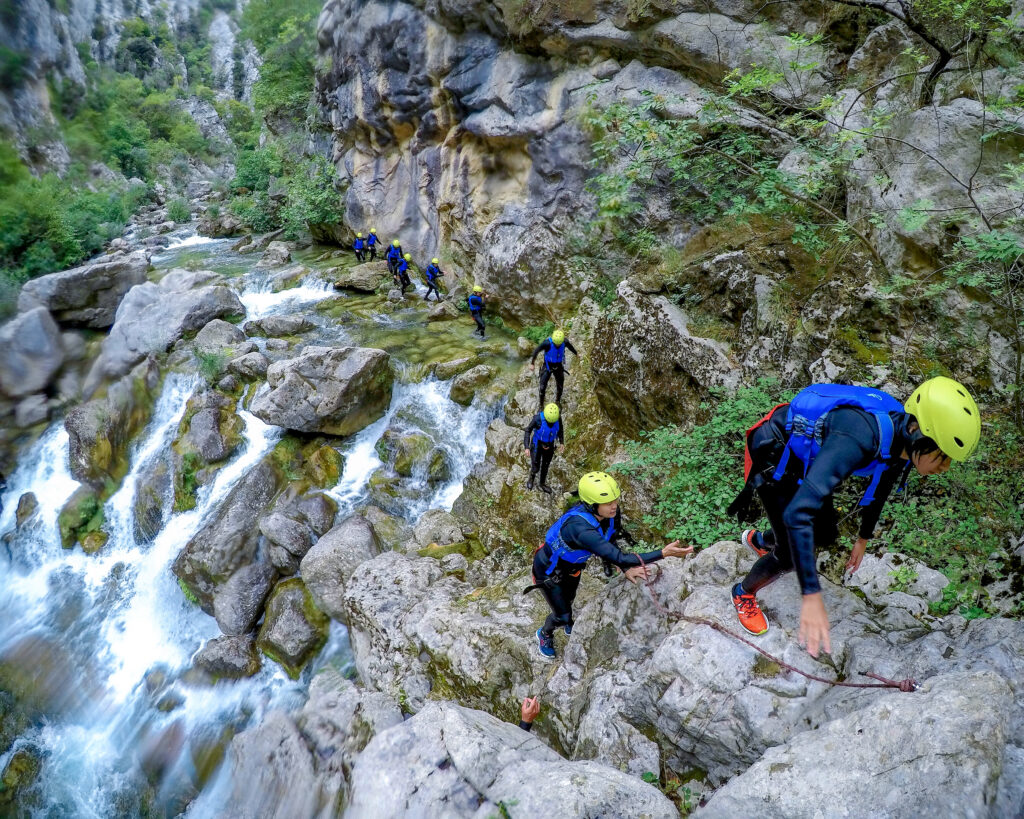 group hiking across a river waterfall in croatia