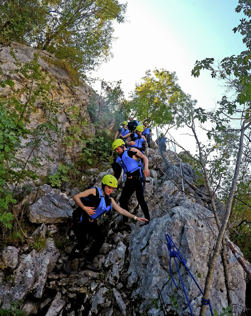 hikers in canyoning gear hiking down rock