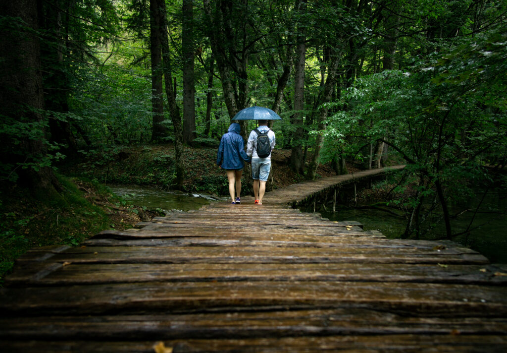 couple on a boardwalk in the rain in plitvice national park