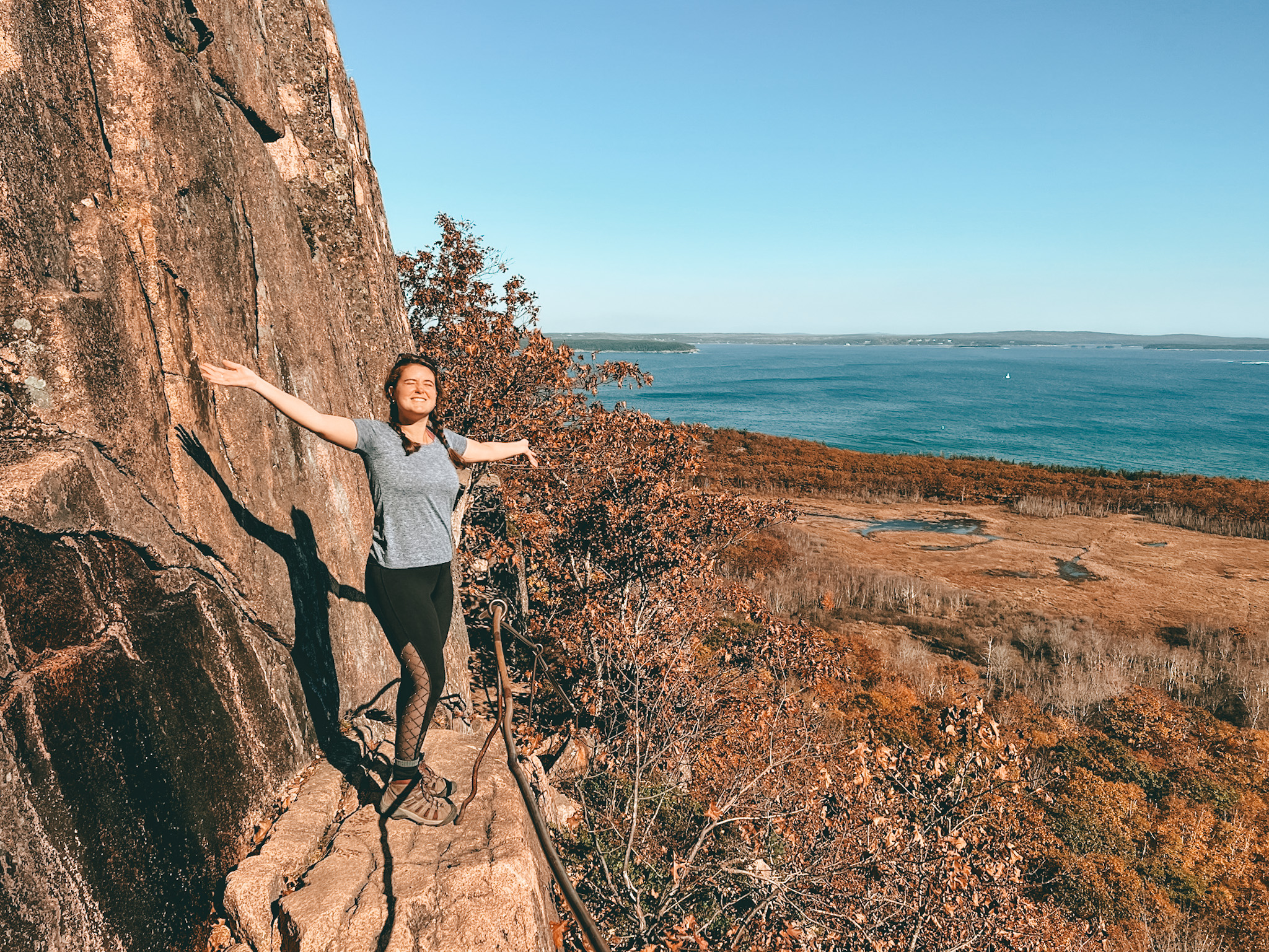 woman hiker with arms up on the precipice trail in acadia